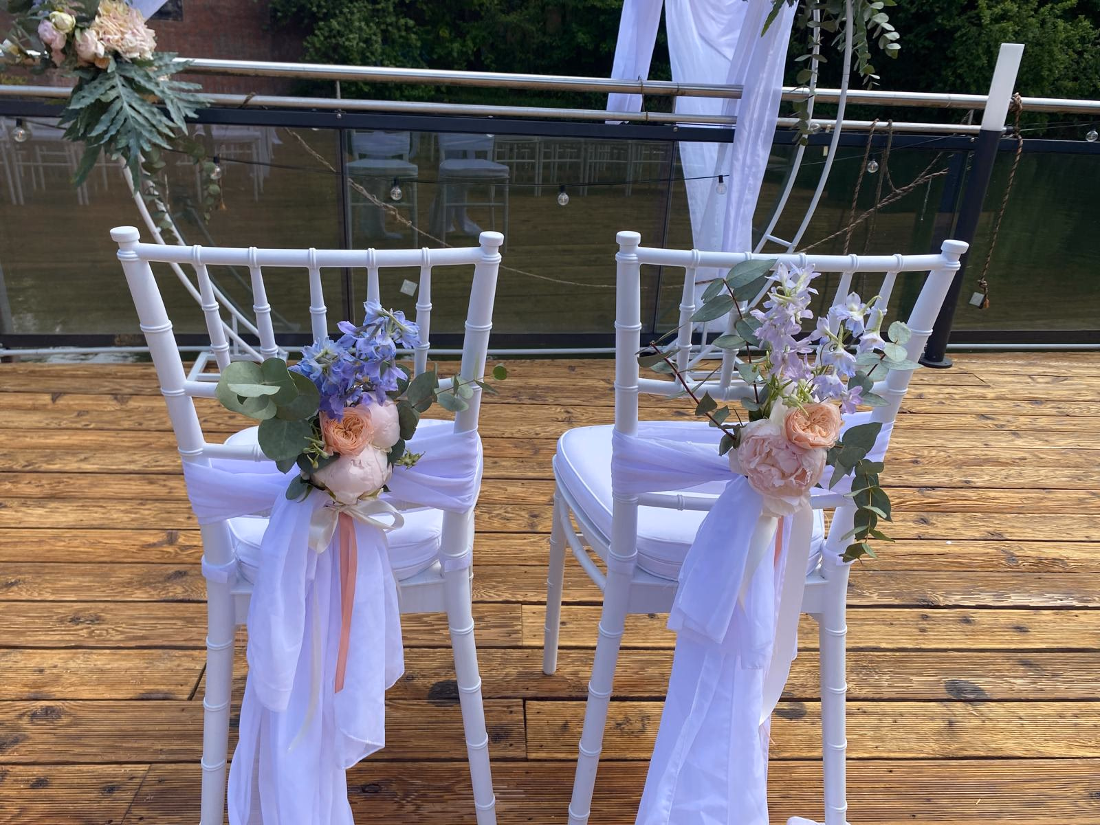 Brautpaar-Chiavari-Stühle mit Hortensie, Gartenrose und Eukalyptus am Wasser, Chiffon-Schärpe.