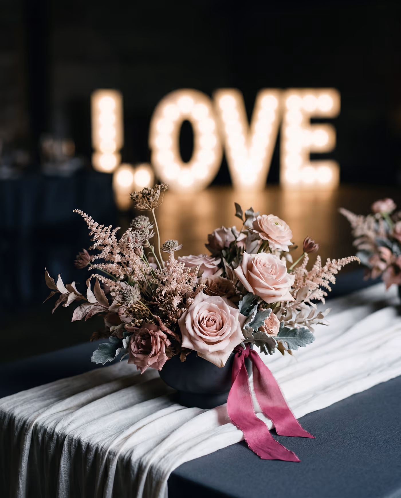Leuchtende LOVE-Lettern hinter einem Blush-Arrangement — Atelier Glamelia